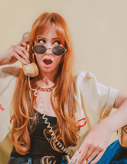 A stylish woman holding a vintage phone, wearing sunglasses.
