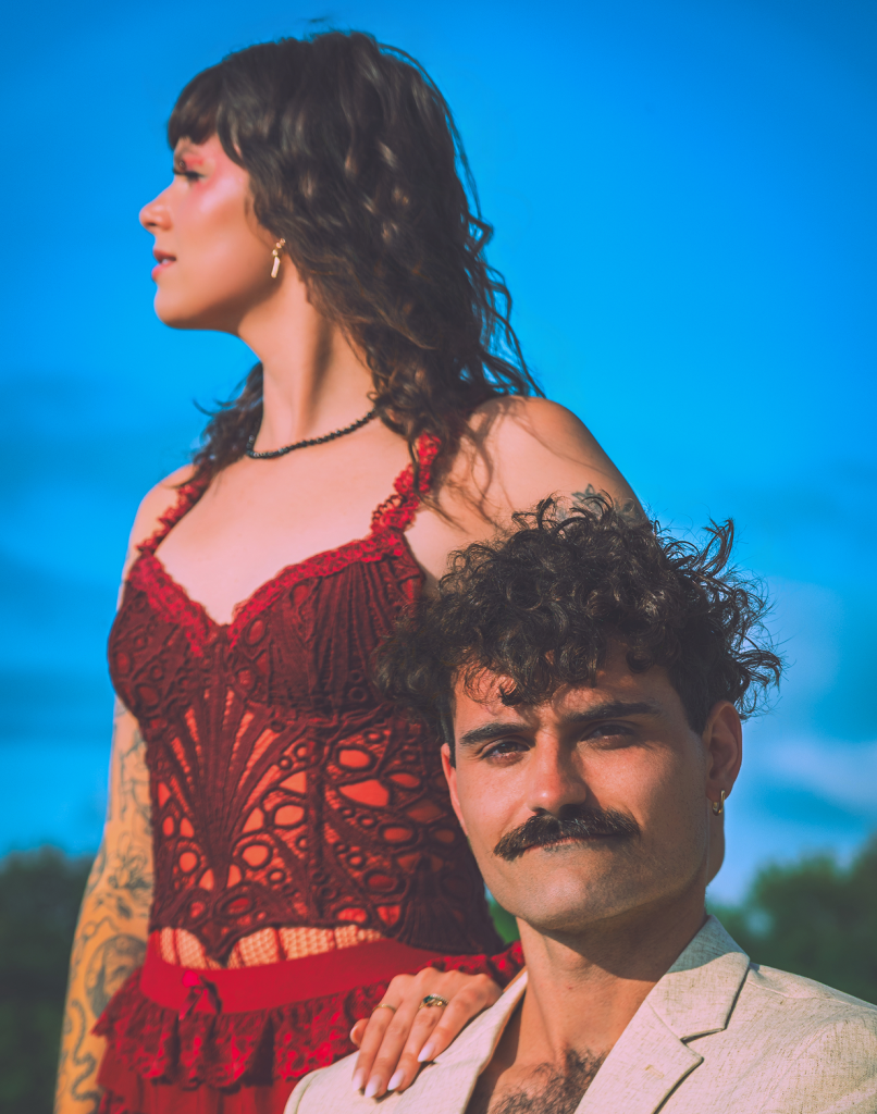 Stylish couple in vibrant clothing against a blue sky.