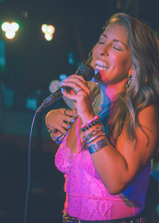 Singer performing live with microphone, vibrant stage lighting.